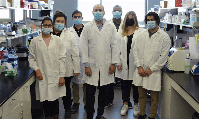 Nadeem Khan and team wearing white coats in lab