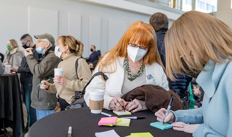 People at table writing on sticky notes