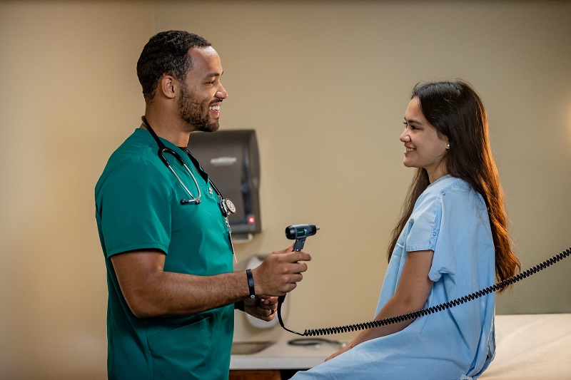 Person in scrubs and person in gown in exam room