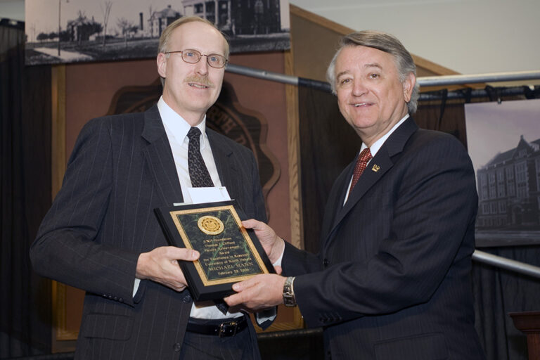 Mike Mann holding plaque with Charles Kupchella