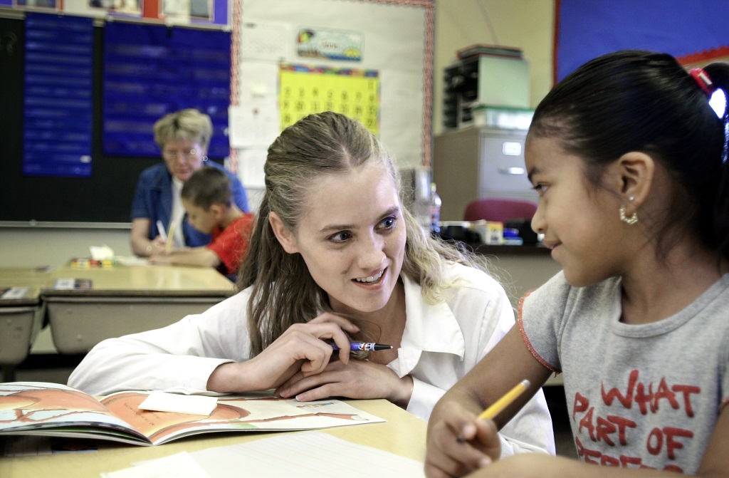 Teacher kneeling next to student