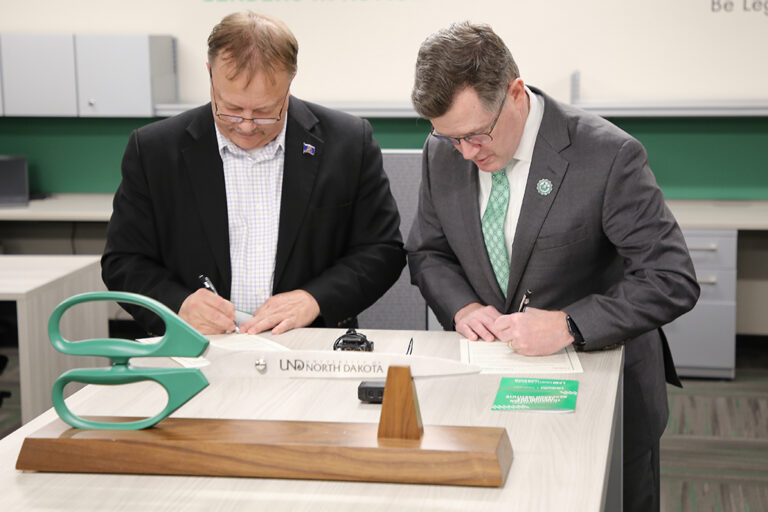 Andrew Armacost and Ronald Henke sign documents