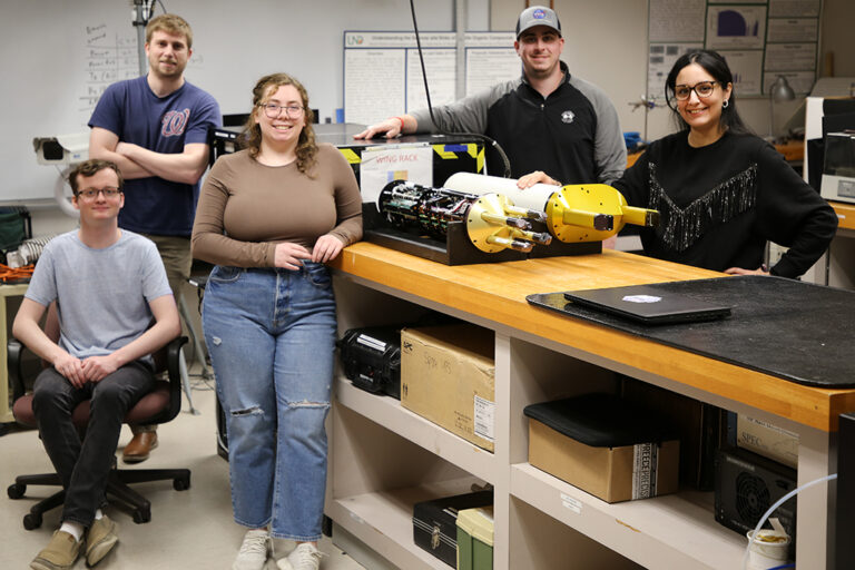 Five people pose around scientific equipment