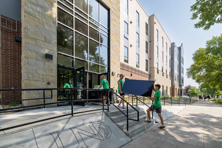 People carrying tv into residence hall