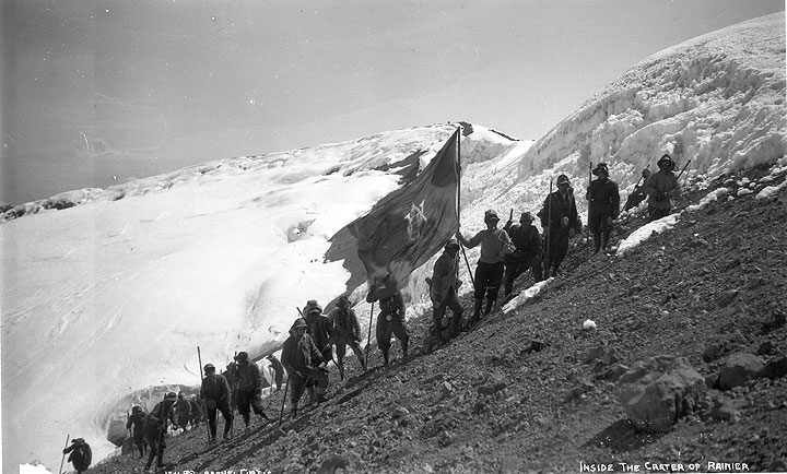 Women mountaineers hold flag on mountainside