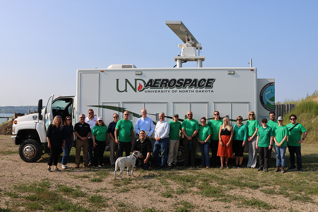 UND people posing for a photo in front of a van