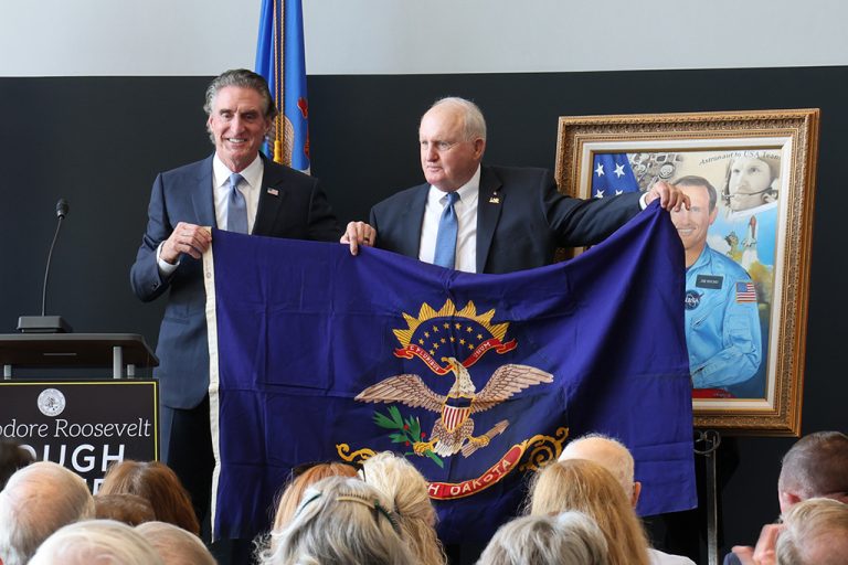 Jim Buchli and Gov. Doug Burgum hold state flag
