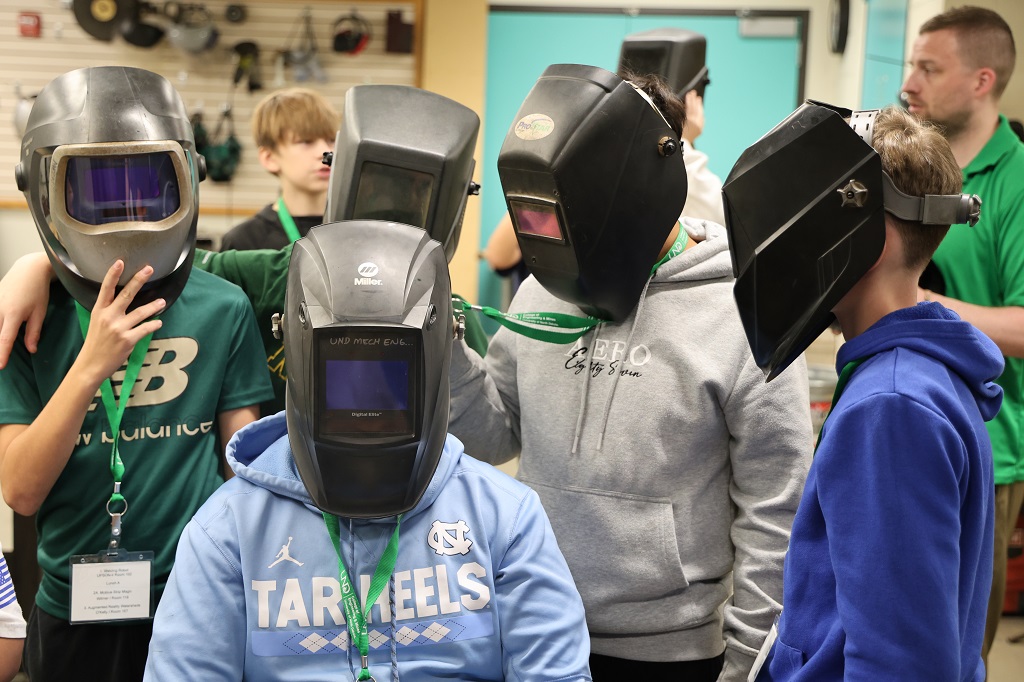 Seventh graders wearing welding helmets.
