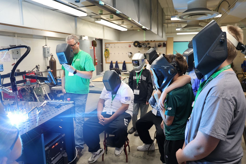 Students and instructor watch welding robot.