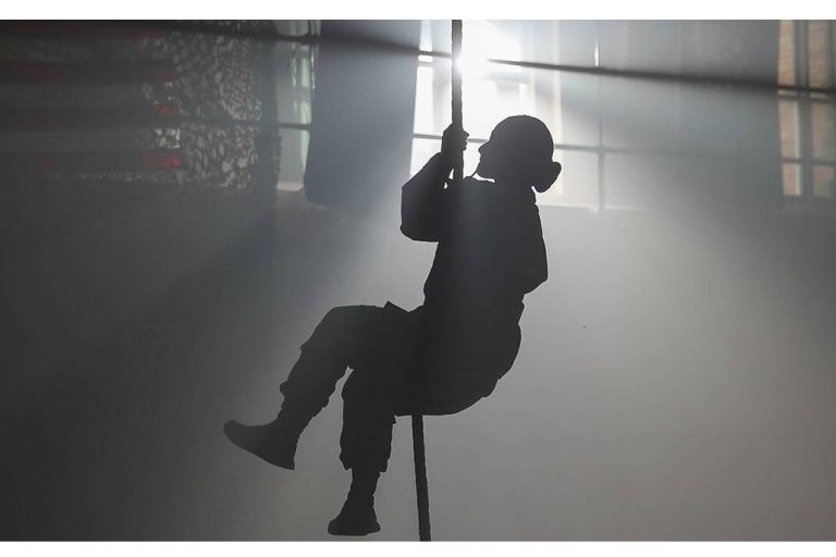 Silhouette of person climbing rope