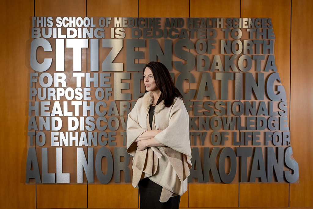 Marjorie Jenkins standing in front of word cloud in shape of North Dakota