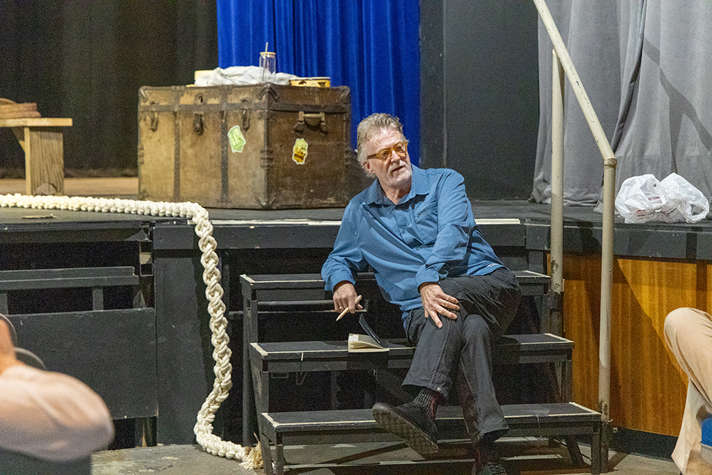 Curt Tofteland, founder of Shakespeare Behind Bars, sits on stage steps.