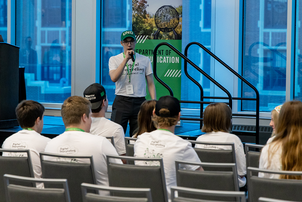 person speaking into a microphone before a group of people.