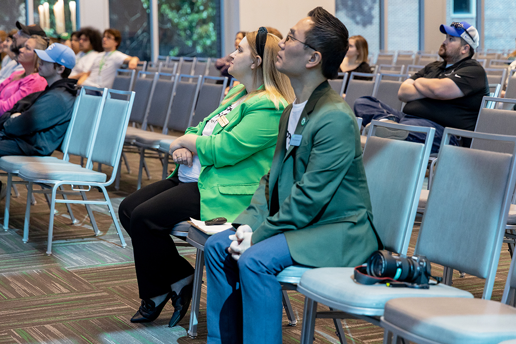 two people sitting on chairs listening to a speaker