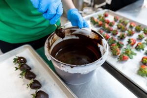 UND Dietetics student Kari Knable in action dipping strawberries in chocolate.