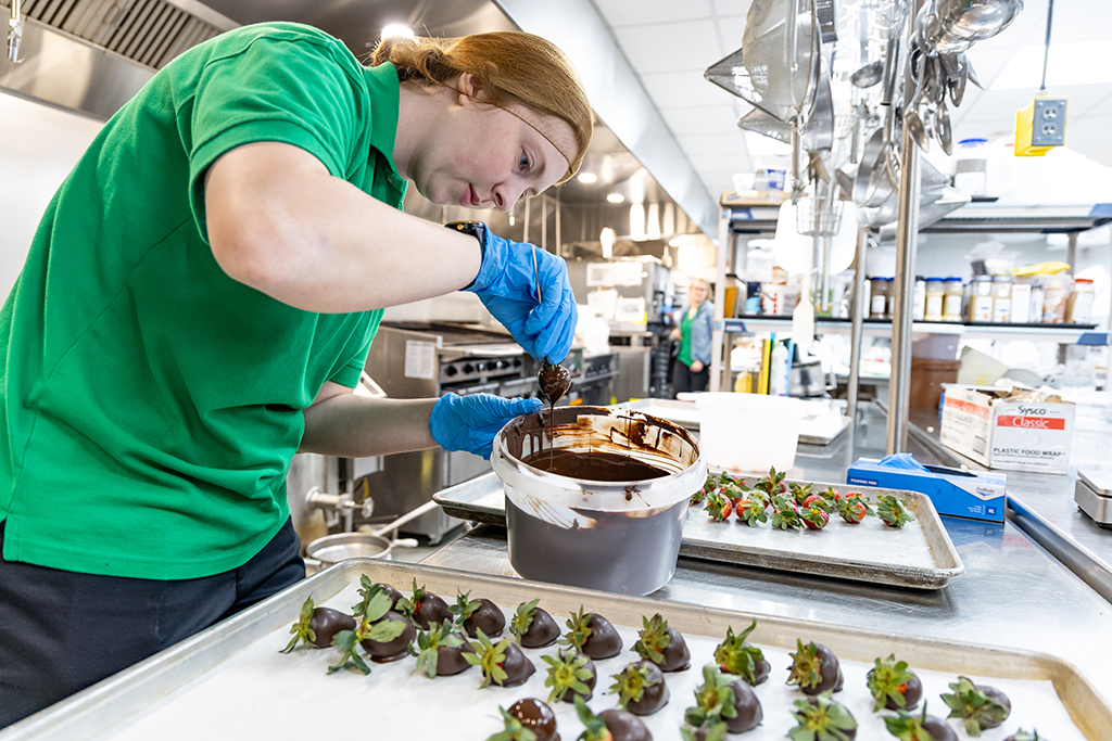 UND Dietetics student Kari Knable carefully twirls a strawberry in dark chocolate. 