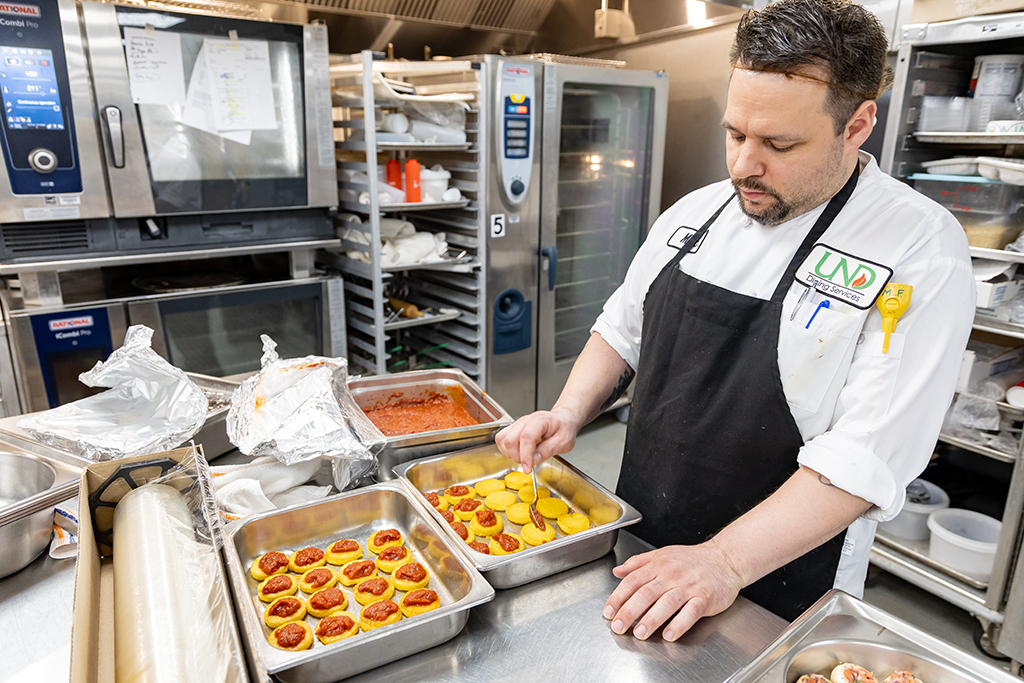 Lead Catering Chef Matt Fashingbauer spoons the red sauce onto his family recipe of Fried Polenta with Braised Beef and Red Sauce.