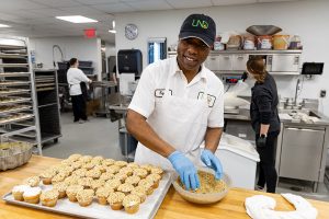Tayun Jones dips frosted cupcakes into a bowl of nuts.