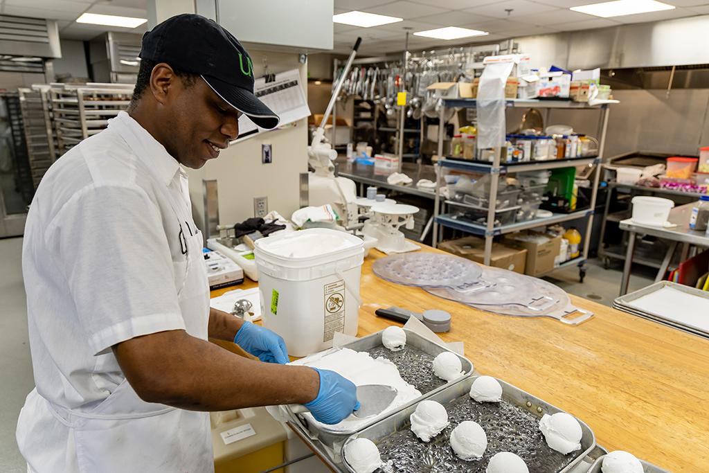 Baker Tayun Jones scoops tasty whip onto the Chocolaty Delicious Cake.