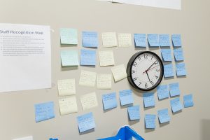 A wall is covered with words of praise and thanks written on sticky notes.