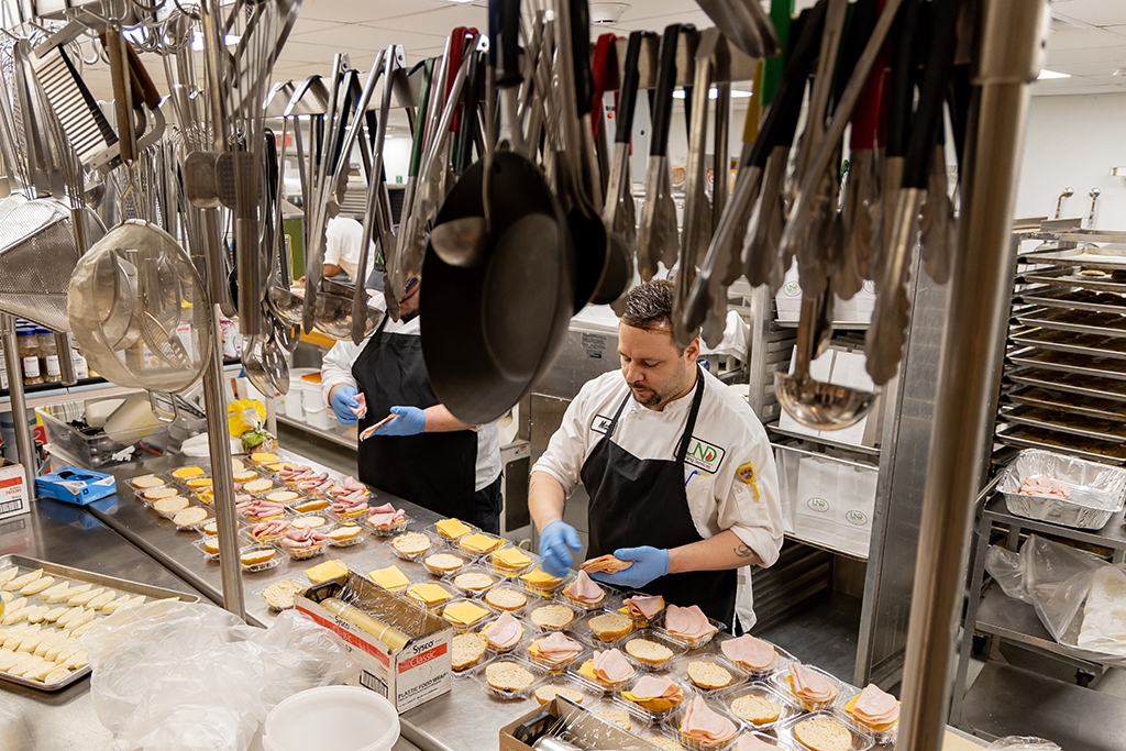 Lead Catering Chef Matt Fashingbauer and Catering Chef Micheal Longwell put together sandwiches for bag lunches ordered for a Forensic Science student field trip. 
