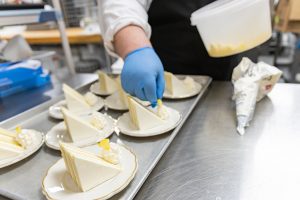 Catering Chef Micheal Longwell puts the final flair on the lemon cream cake for the Be Bold: Women in Leadership Luncheon.
