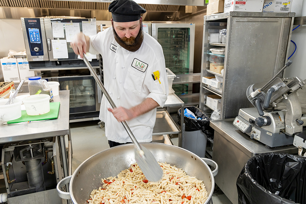Executive Chef for Retail Dining Mitch Vervalen uses a huge paddle and a bowl called The Bird Bath to make quick work of coating a locally sourced pasta salad with homemade dressing.
