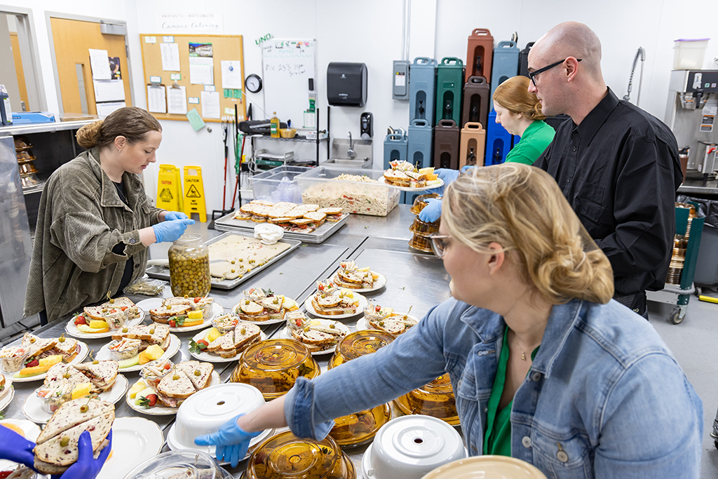 UND Catering Manager Andrea Green (foreground) makes sure the food makes a seamless transition from the main kitchen to the separate service kitchen area where it is plated for the full-service event.