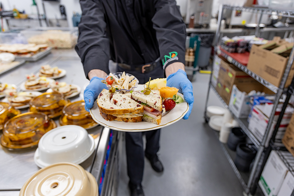 A server holds out a beautiful plate prepared for a full-service luncheon.