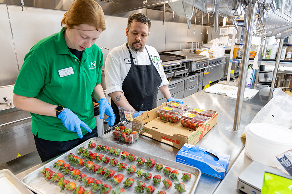 UND Dietetics student Kari Knable counts out the number of strawberries she’ll need to dip in dark chocolate as Lead Catering Chef Matt Fashingbauer shows her the ropes. 
