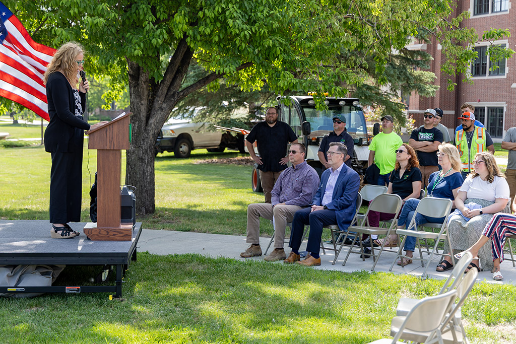 People listening to a woman speak at a podium