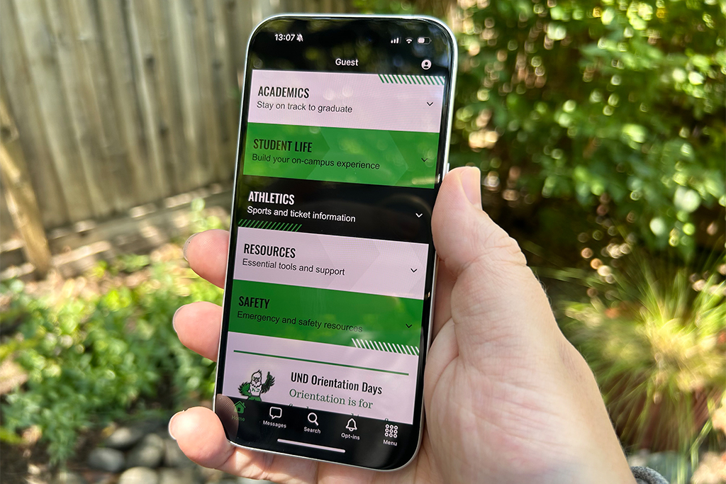 Hand holding phone with My UND app home page displaying