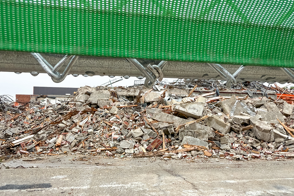 The rubble of the Hyslop Sports Center is piled high beyond a protective fence.