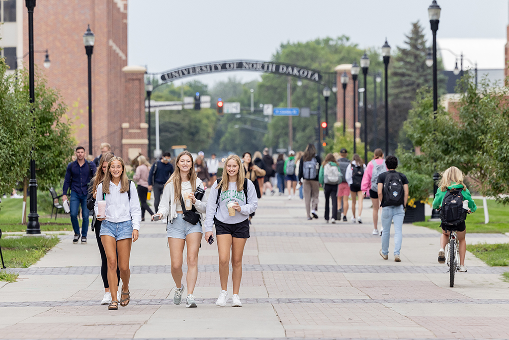 Students walk, ride and roll down a busy sidewalk in the heart of campus.