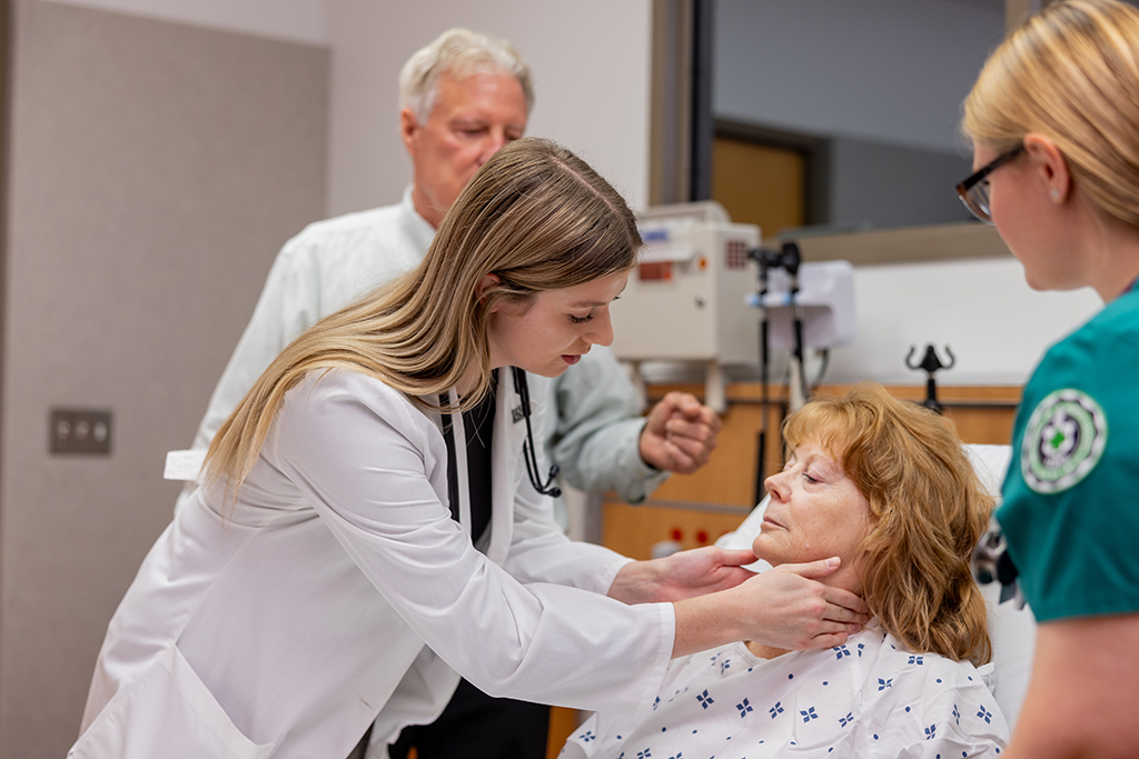 Student performs examination on patient as senior doctor looks on