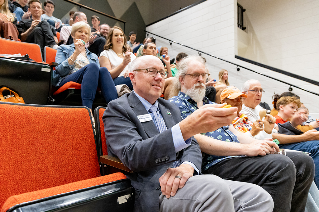 Dean Brad Rundquist shakes his musical instrument on cue.