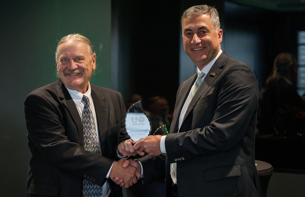 Arne Vasenden accepts award from and shakes hands with Bob Kraus