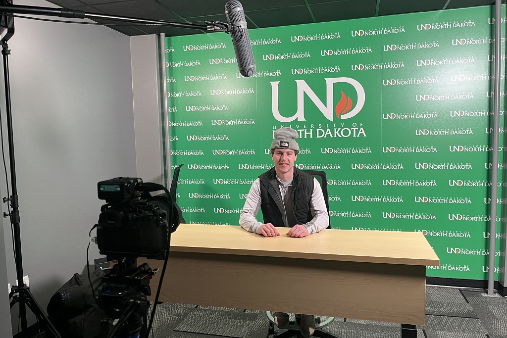 Lincoln Retzlaff sits in a podcast studio at UND.