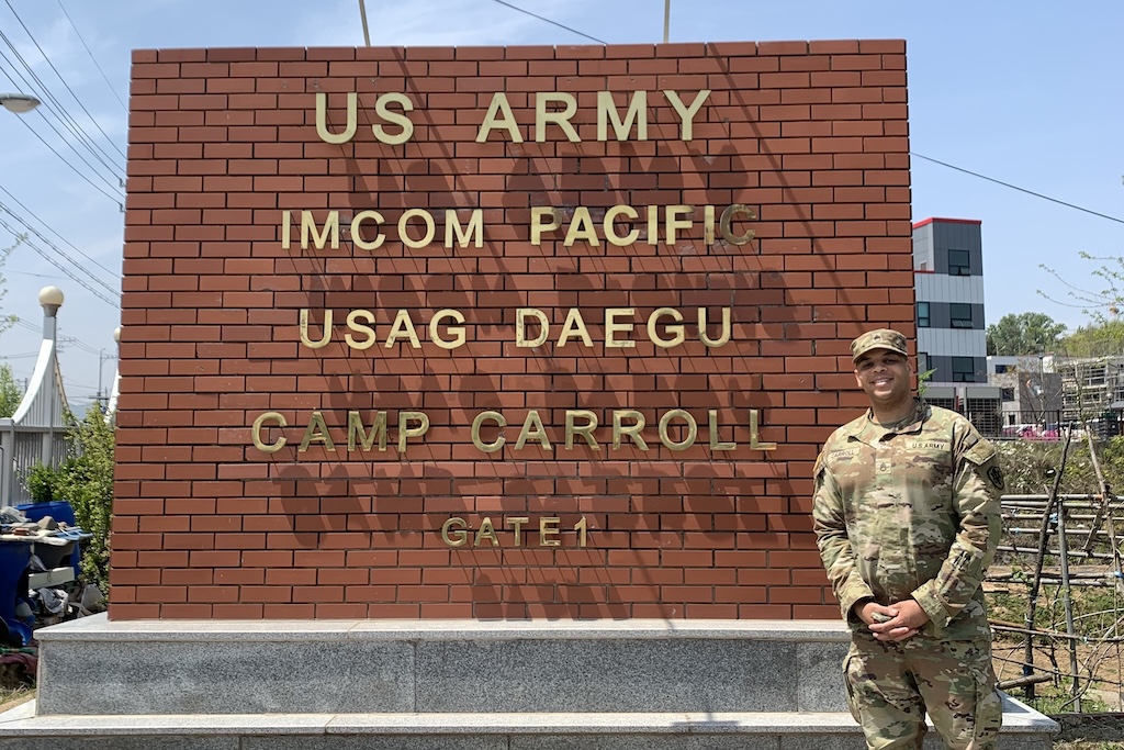 Soldier stands in front of US Army Camp Carroll sign