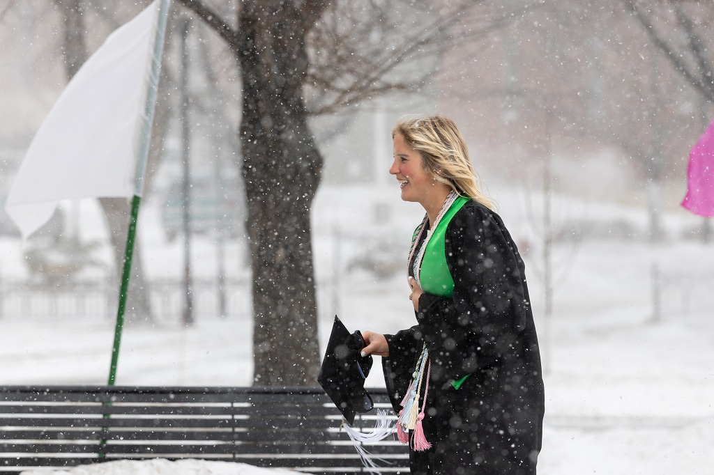 UND graduate smiles as she walks outside in the snow during UND's Winter Commencement 2025.