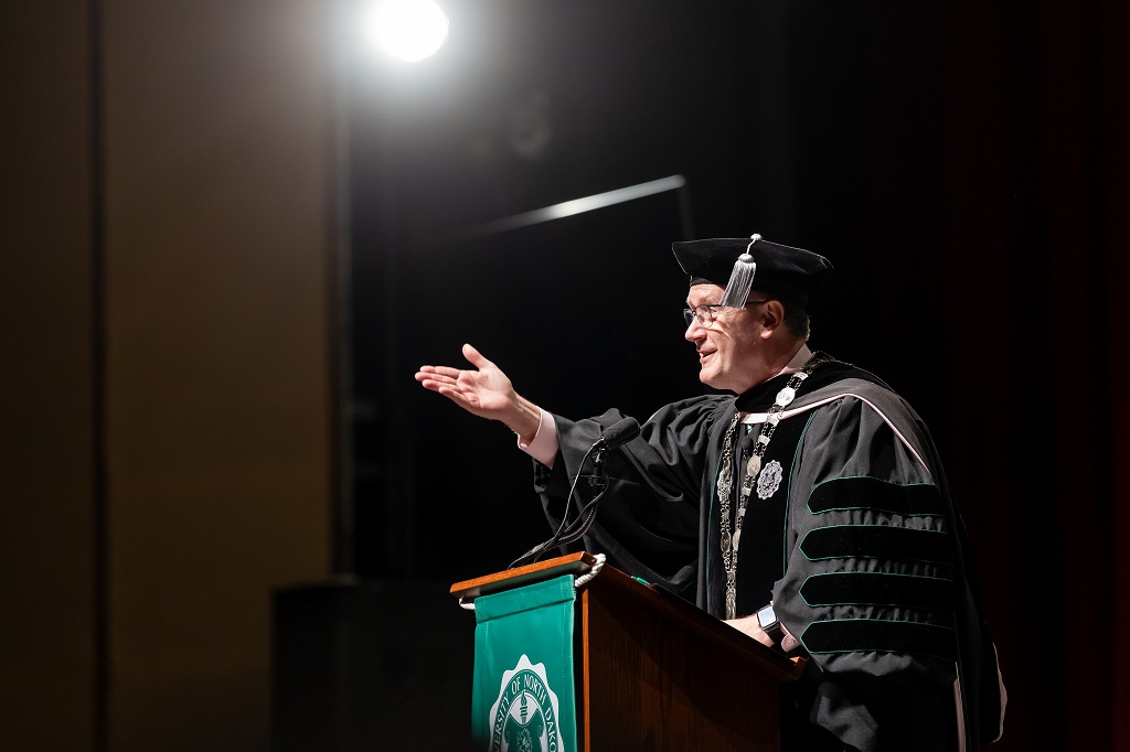 UND President Andy Armacost, at a podium, congratulates graduates during Winter Commencement 2025