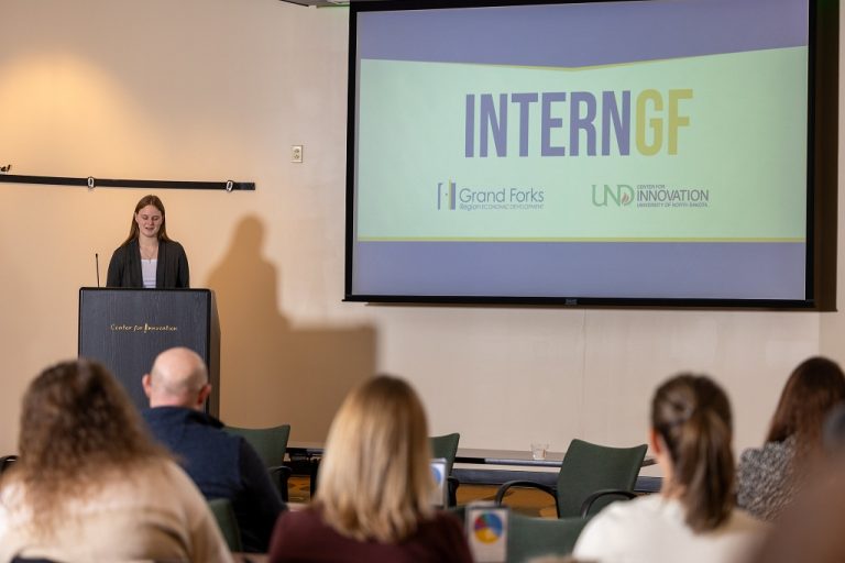 A student at a podium talks while a slide is shown on a nearby screen