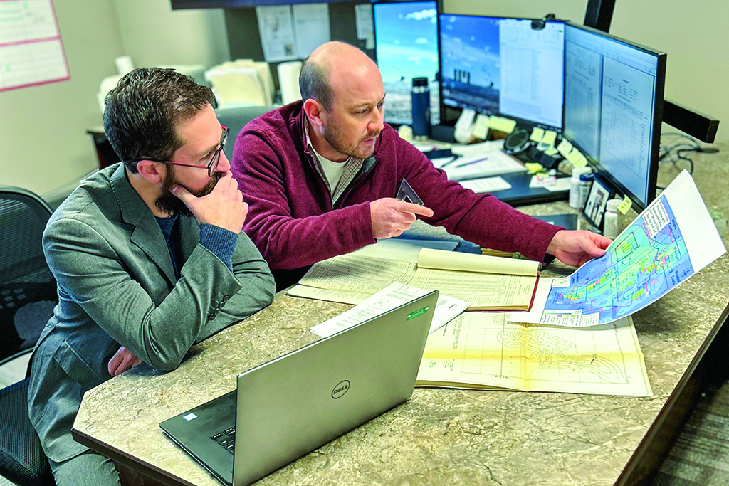 Two men sit at a computer station