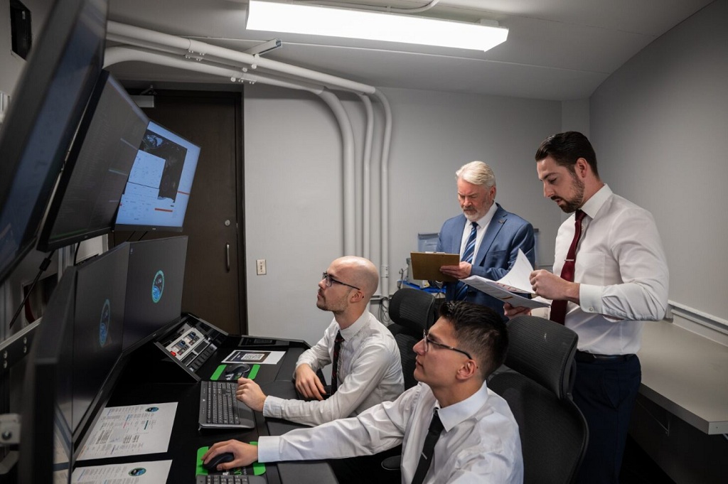 Four people monitor computer displays at Odegard Ground Station on the UND ampus.