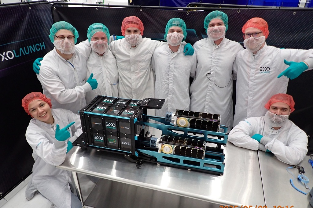 White-coated technicians stand around the UND satellites in a "clean room."