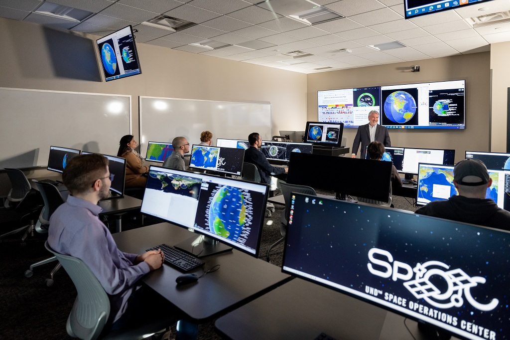 Students sit behind computers in classroom