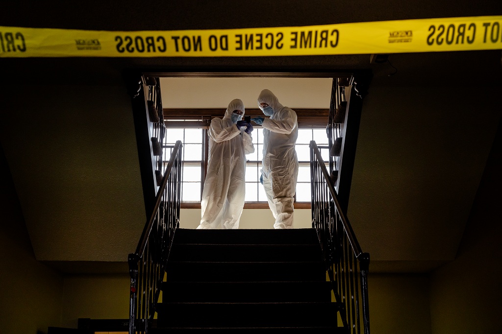 With 'Crime Scene' tape in the foreground, UND students in hazmat gear learn crime-scene investigation in Gustafson House.