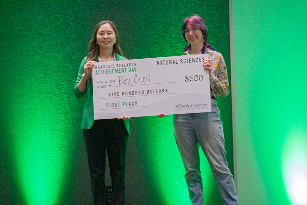 Soojung Kim presenting large check to Bex Cecil for first place prize