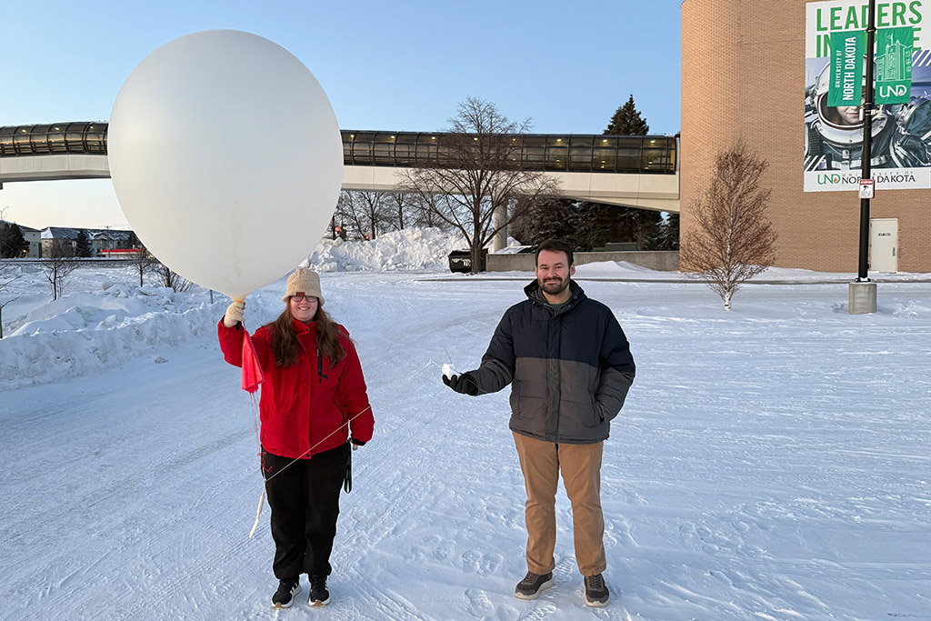 two people prepare to release a weather balloon
