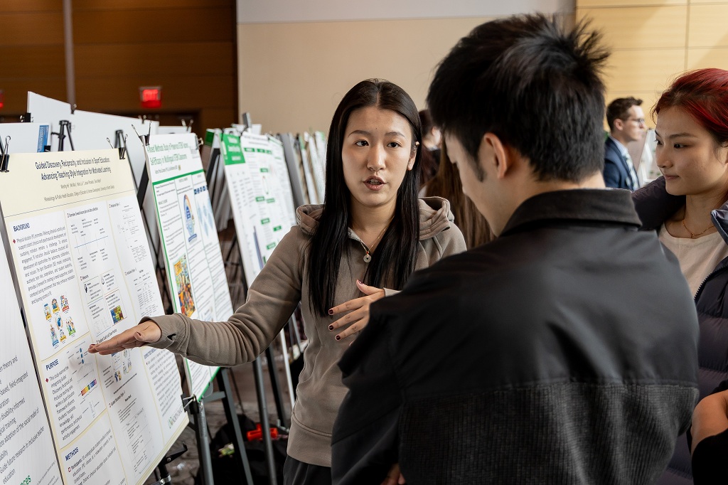 Conference participants discuss research poster at conference